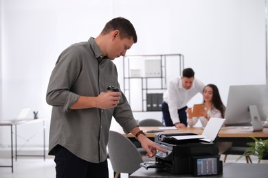 Photo of Employee using new modern printer in office