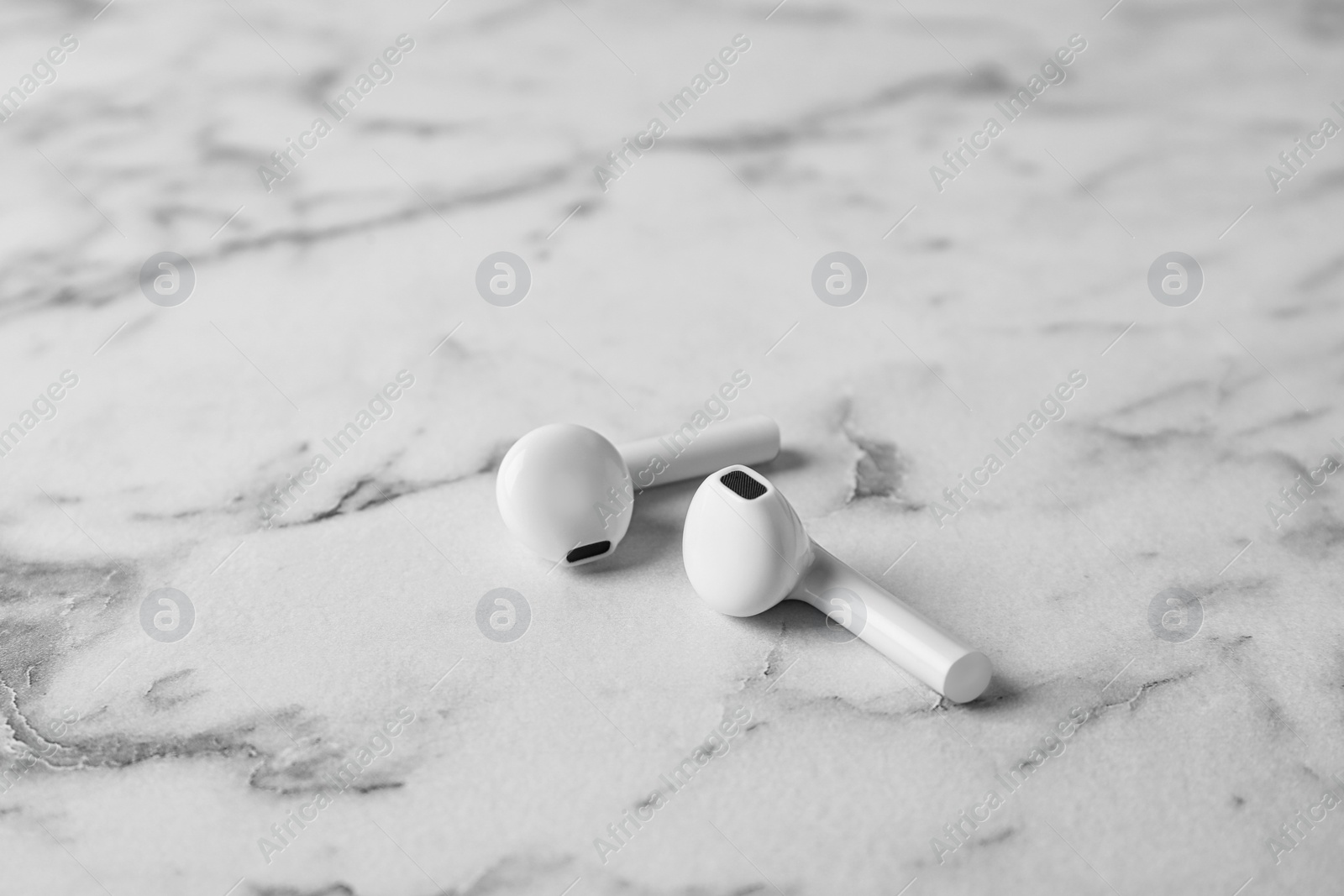 Photo of Pair of modern wireless earphones on marble table