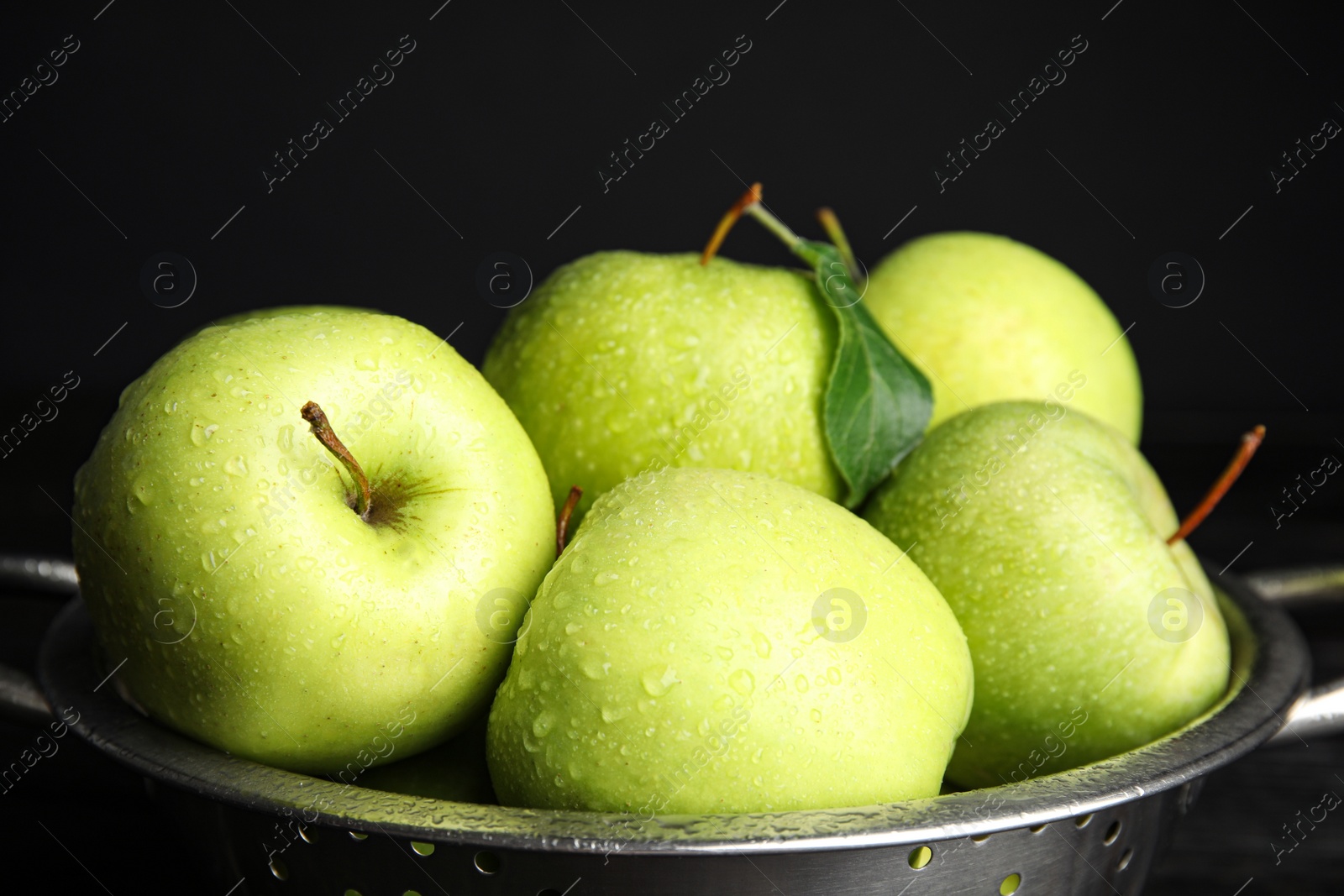 Photo of Colander of fresh ripe green apples on black background, closeup view