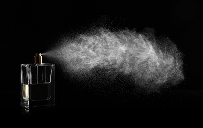 Photo of Woman spraying luxury perfume on black background, closeup