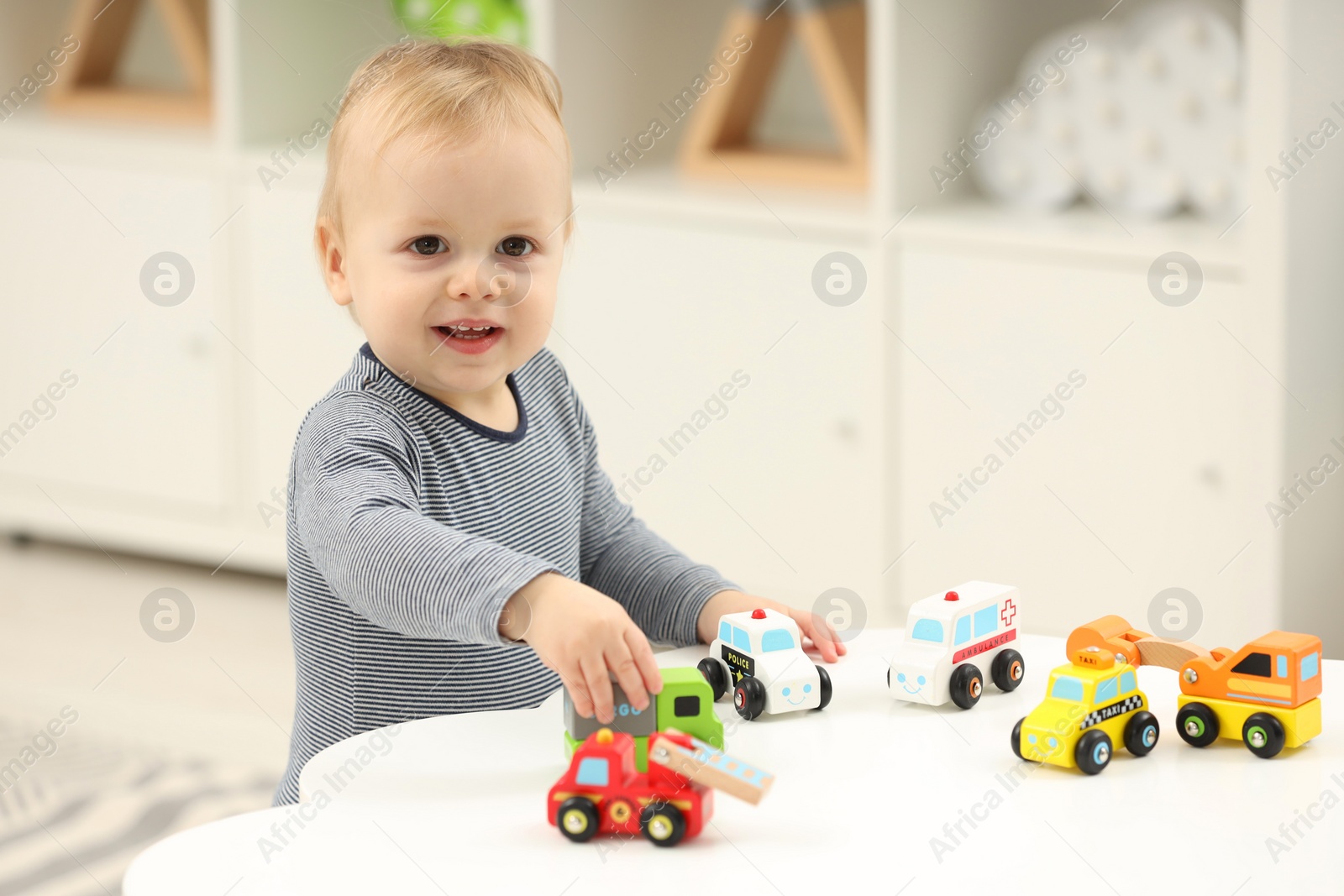 Photo of Children toys. Cute little boy playing with toy cars at white table in room, space for text