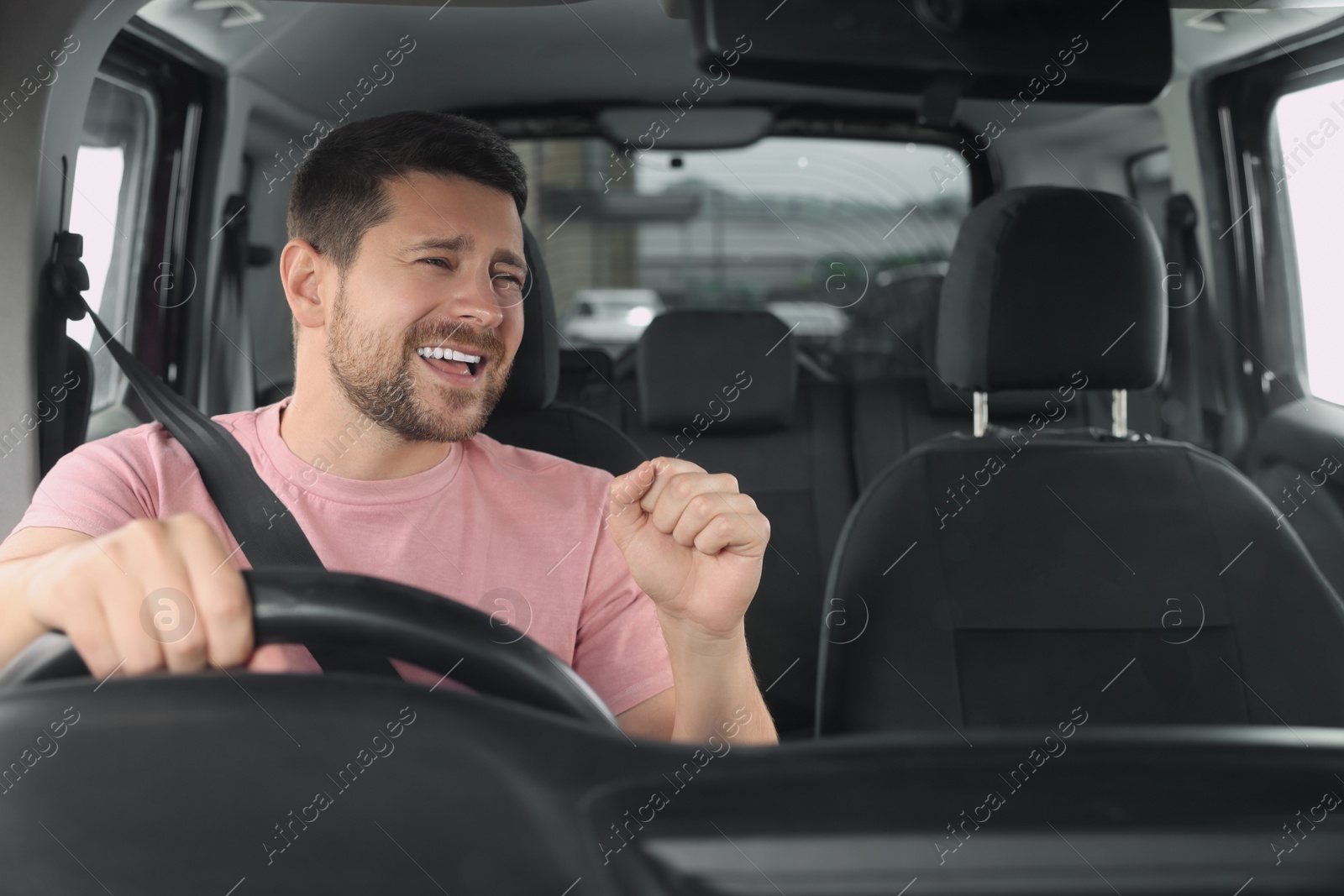 Photo of Listening to radio. Handsome man enjoying music in car, view through windshield