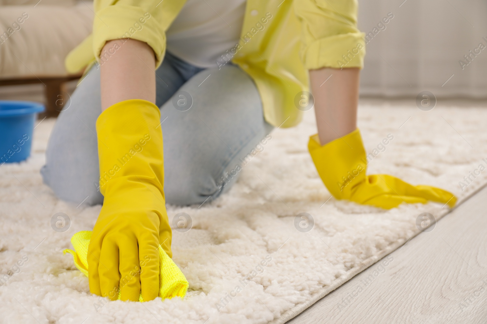 Photo of Woman in rubber gloves cleaning carpet with rag indoors, closeup