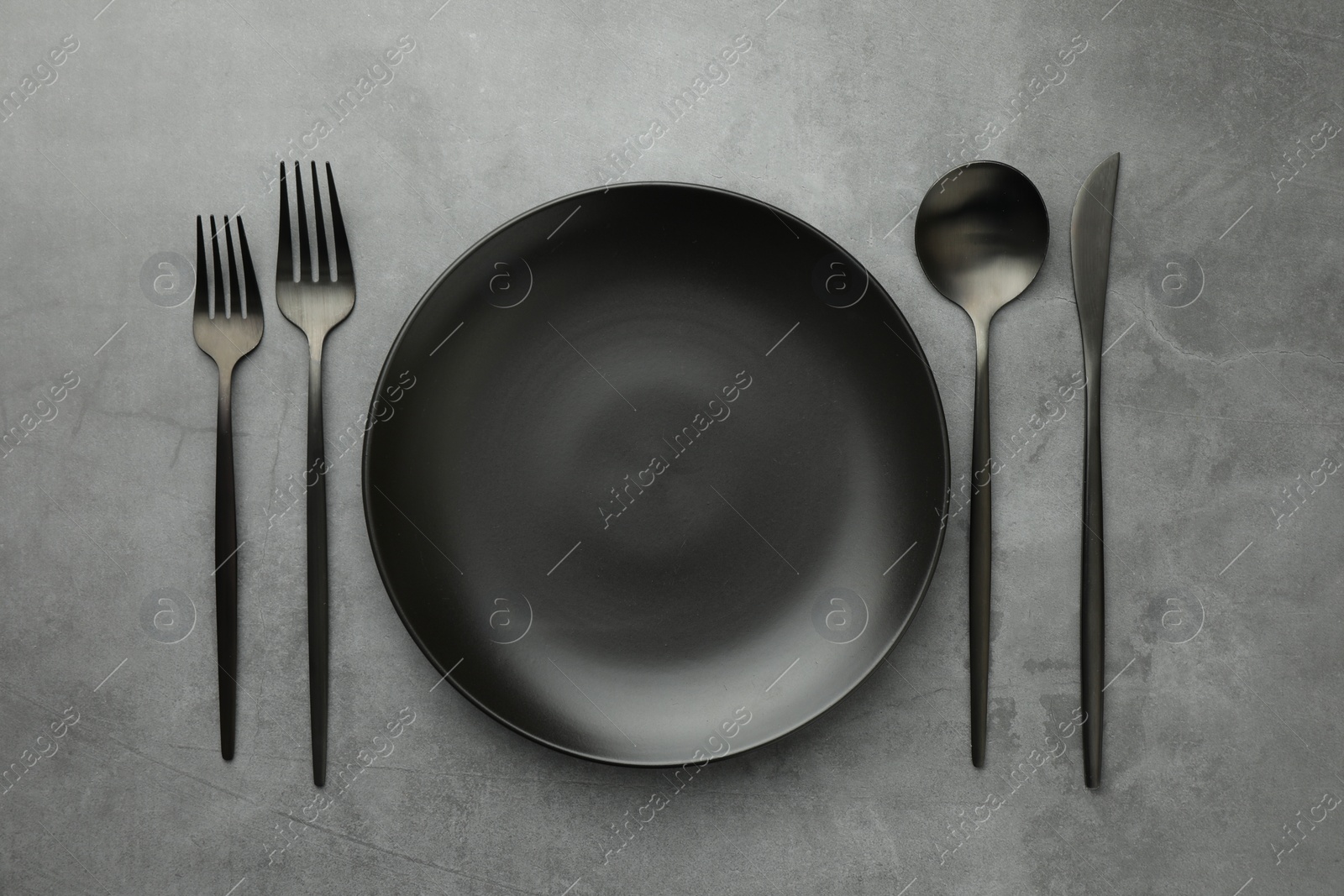 Photo of Empty plate and cutlery on grey table, flat lay