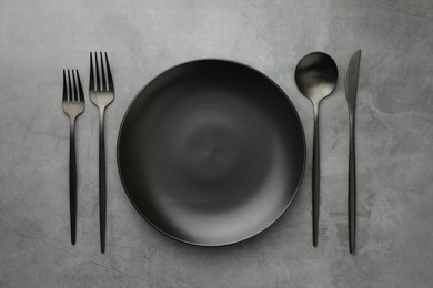 Empty plate and cutlery on grey table, flat lay