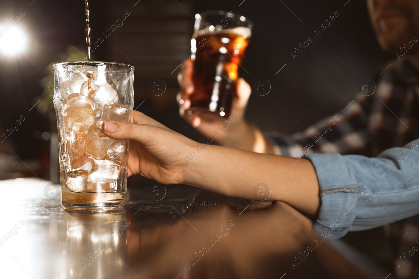 Photo of People with cola in glasses at bar counter indoors, closeup. Pouring beverage