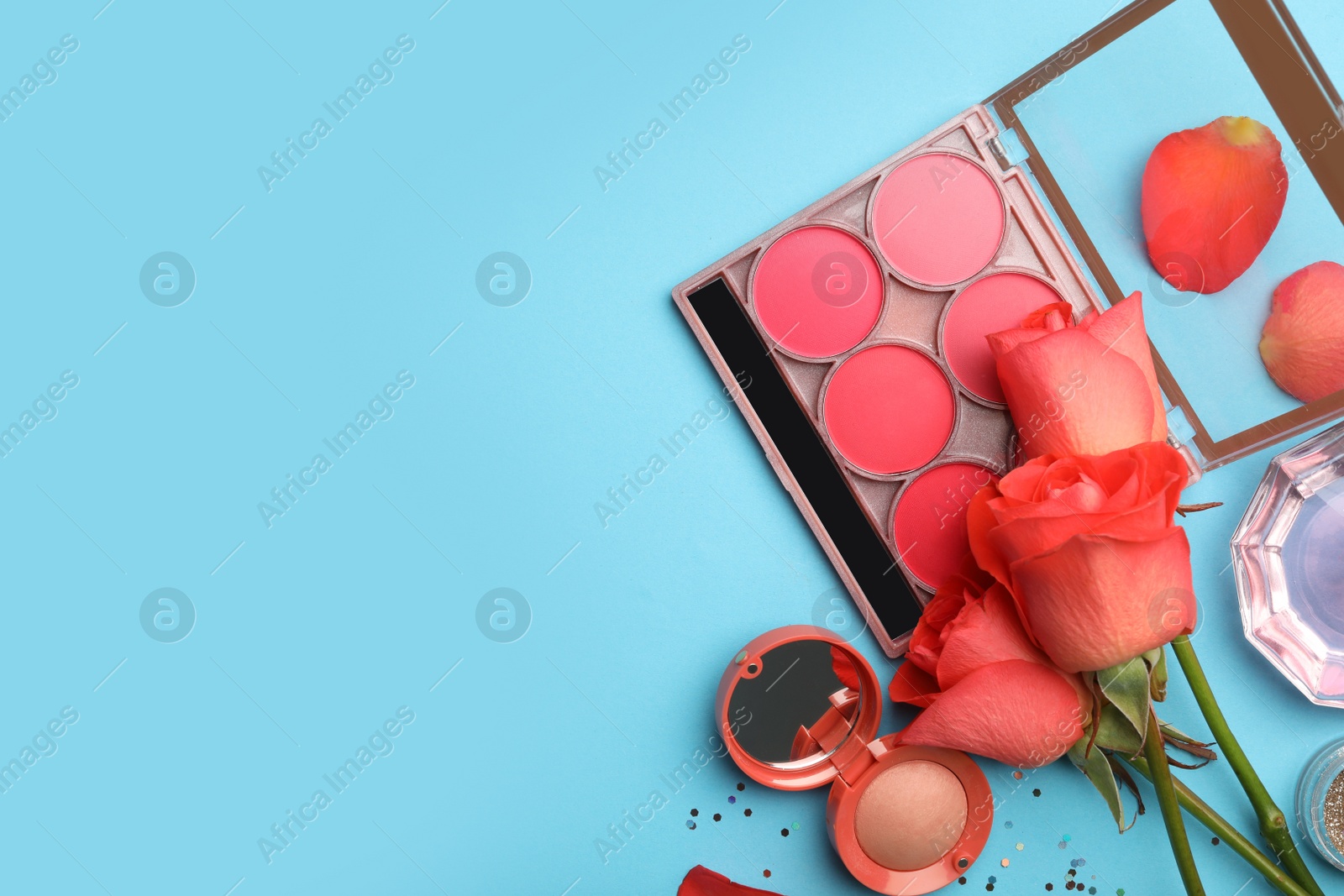 Photo of Flat lay composition with coral cosmetics and flowers on light blue background. Space for text