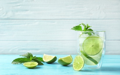 Photo of Natural lemonade with lime and mint in glass on wooden table