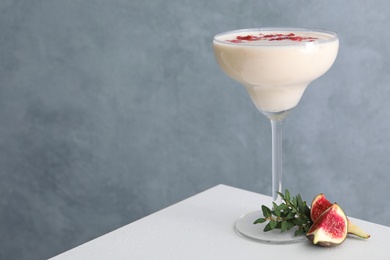 Photo of Delicious fig smoothie in glass on white table. Space for text