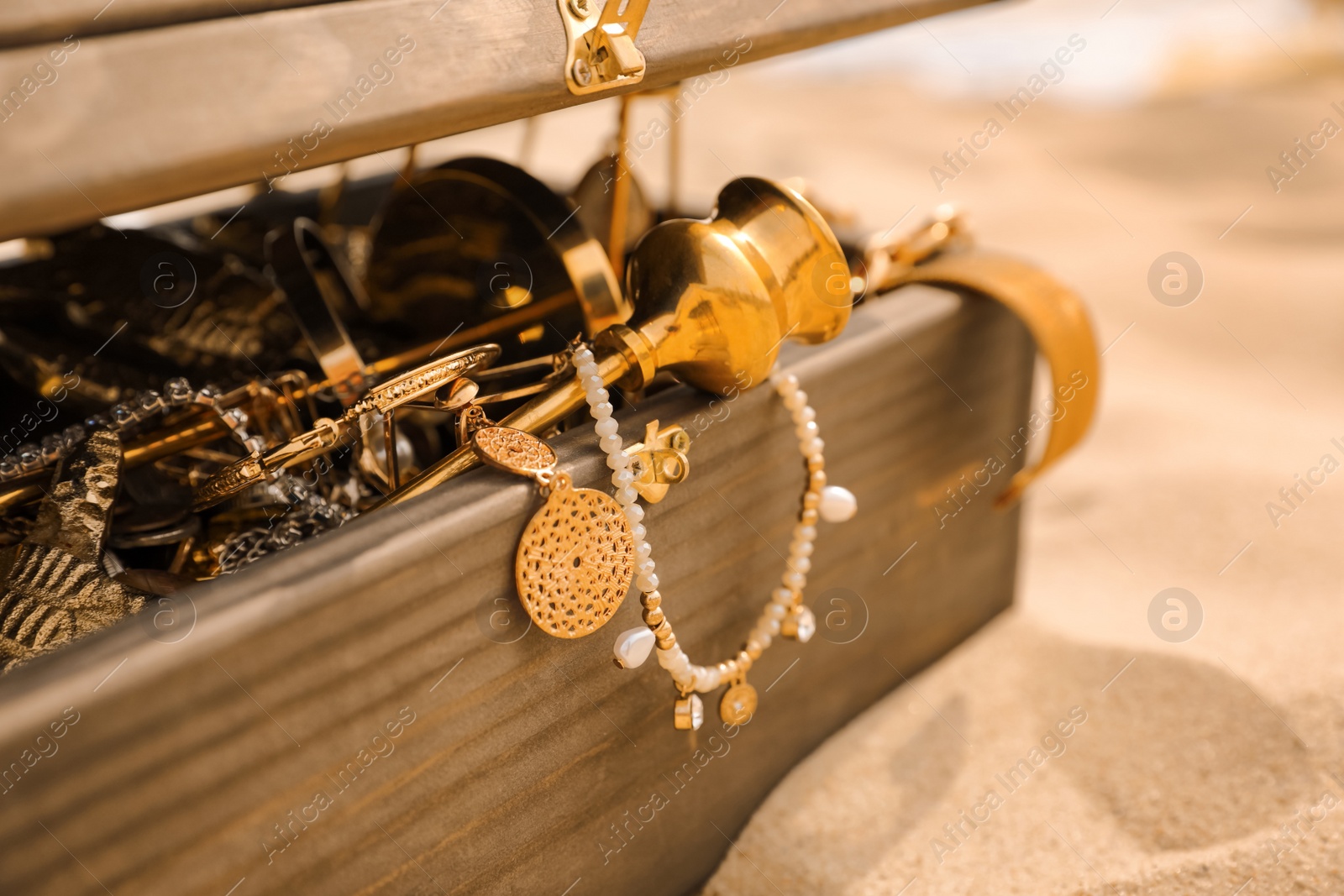 Photo of Open wooden treasure chest on sandy beach, closeup