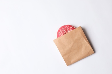 Photo of Paper bag with glazed doughnut on white background, top view. Space for text