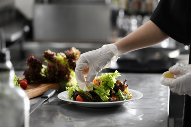 Female chef cooking tasty food in restaurant kitchen, closeup