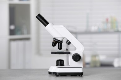 Photo of Modern medical microscope on grey table in laboratory