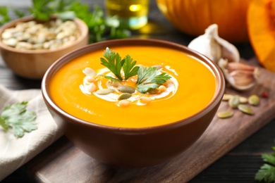 Photo of Delicious pumpkin soup in bowl on wooden table