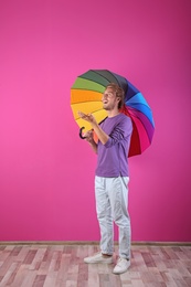 Man with rainbow umbrella near color wall