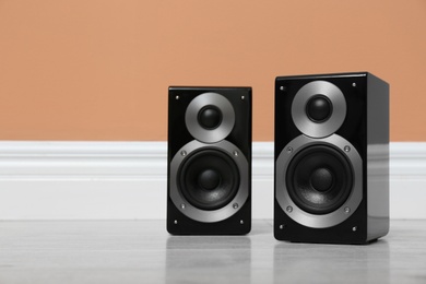 Photo of Modern powerful audio speakers on floor near orange wall