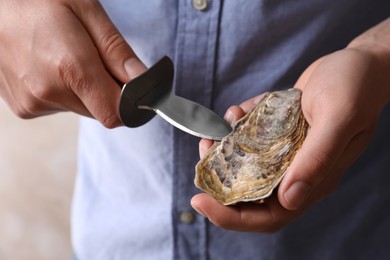 Man opening fresh oyster with knife, closeup