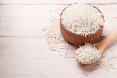 Photo of Raw basmati rice on white wooden table. Space for text