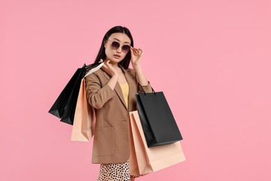 Beautiful woman with shopping bags on pink background. Space for text