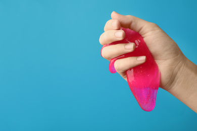 Woman playing with pink slime on light blue background, closeup. Antistress toy