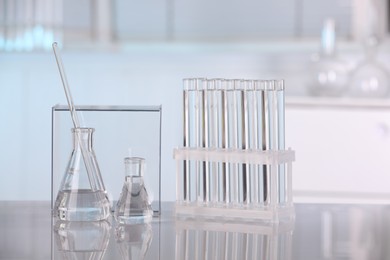 Laboratory analysis. Glass flasks, test tubes and stirring rod on white table indoors