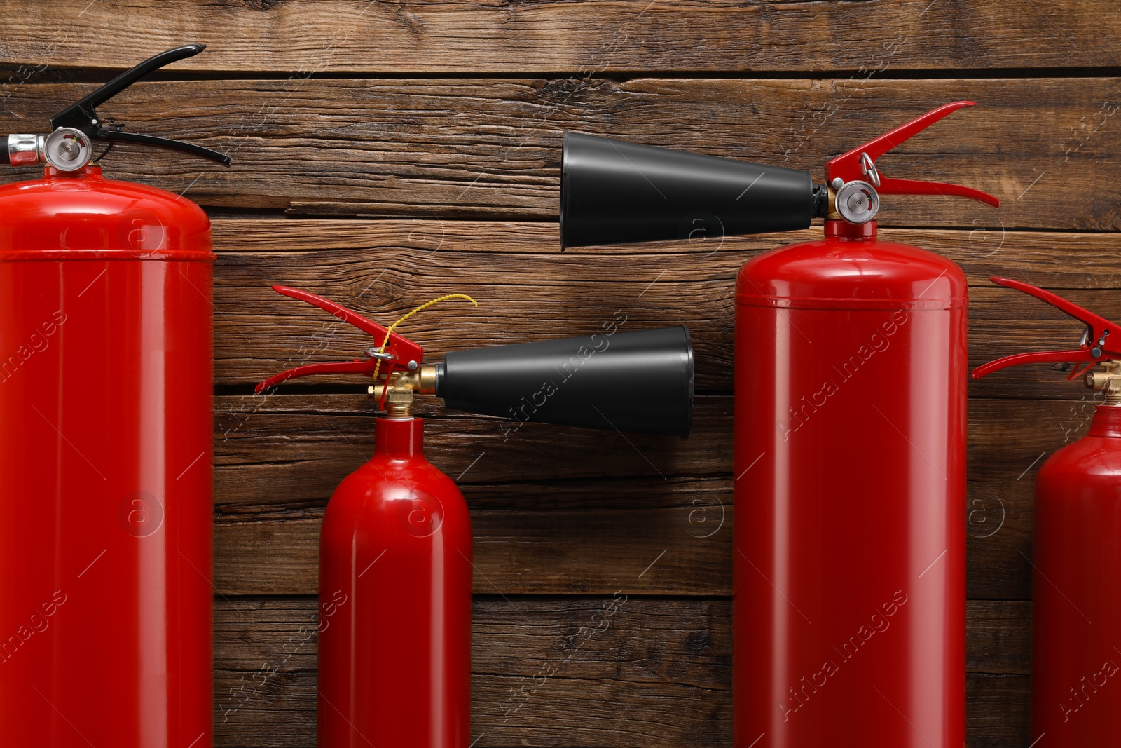 Photo of Many fire extinguishers on wooden background, flat lay