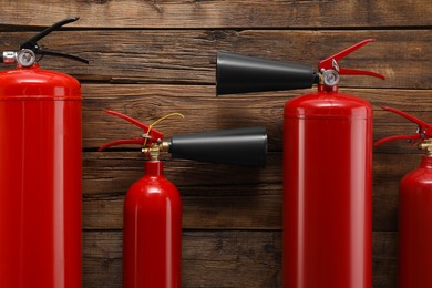 Photo of Many fire extinguishers on wooden background, flat lay
