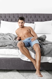 Sexy young man lying on bed with soft pillows at home