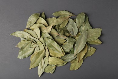 Photo of Pile of aromatic bay leaves on gray wooden table, top view