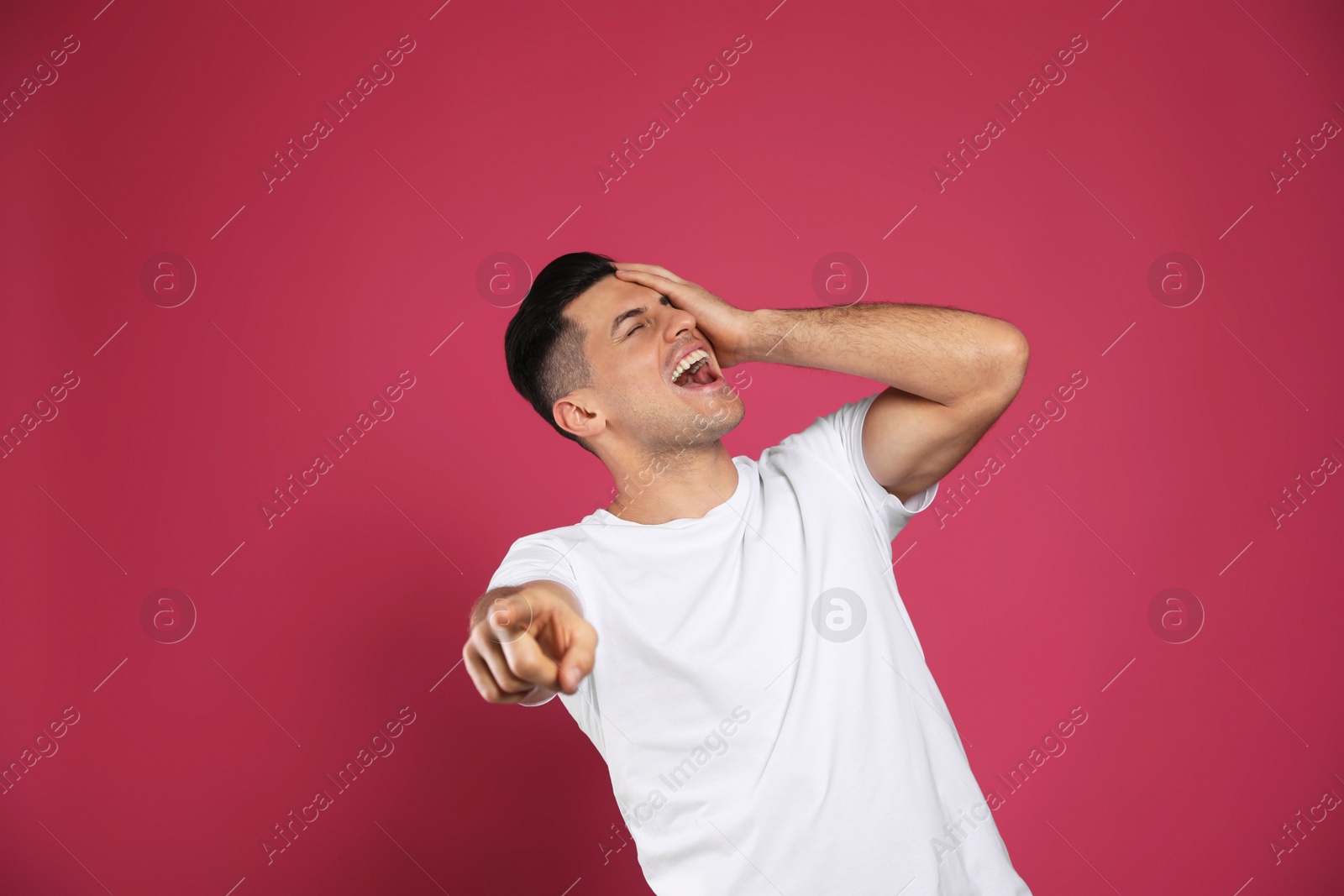 Photo of Handsome man laughing on maroon background. Funny joke