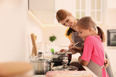 Photo of Mother and daughter cooking together in kitchen. Space for text