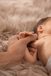 Photo of Father holding hand of his newborn baby, closeup. Lovely family