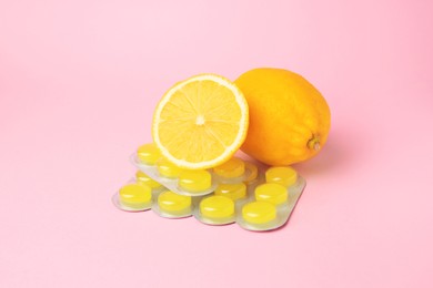 Photo of Blisters with cough drops and fresh lemons on pink background
