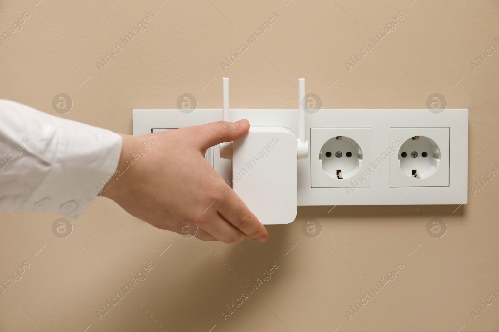 Photo of Woman turning on wireless Wi-Fi repeater indoors, closeup