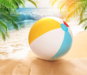 Image of Colorful beach ball on sandy coast near sea