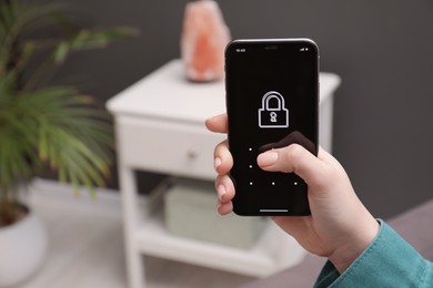 Woman unlocking smartphone with blocked screen indoors, closeup. Space for text