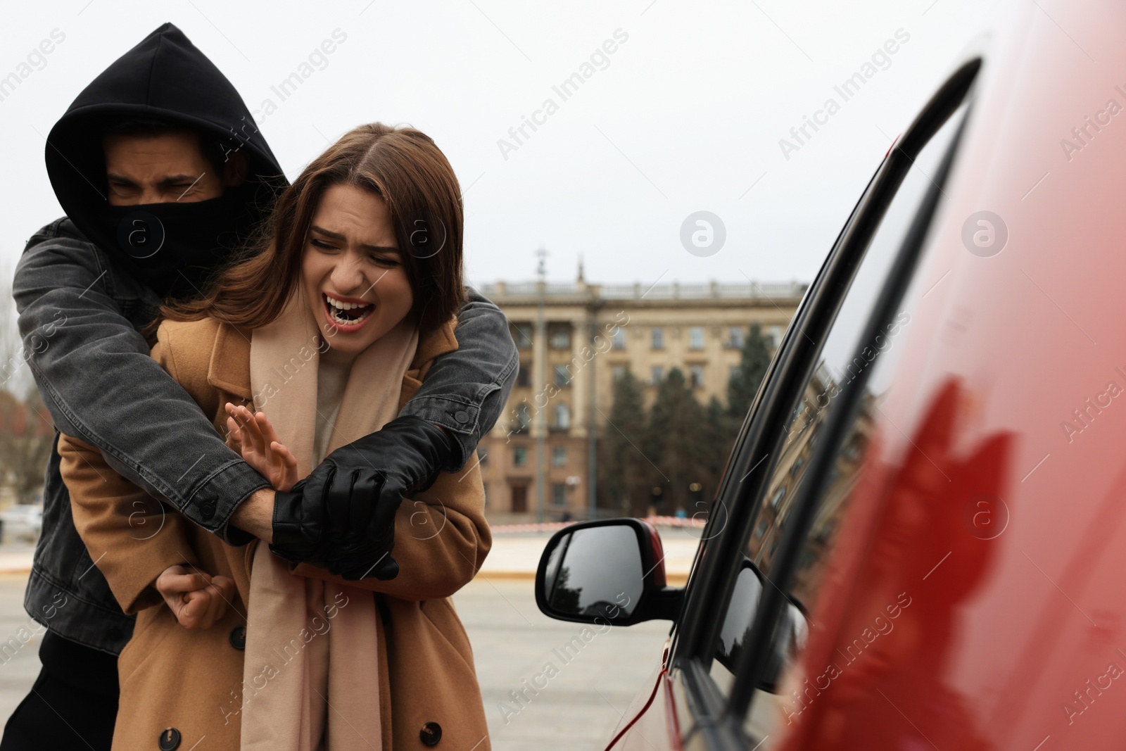 Photo of Woman defending herself from attacker near car outdoors