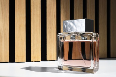 Photo of Bottle of luxury perfume on white table. Space for text
