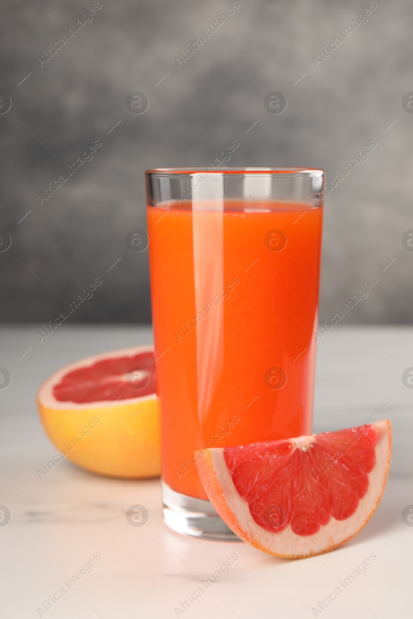 Photo of Tasty grapefruit juice in glass and fresh fruit on white table