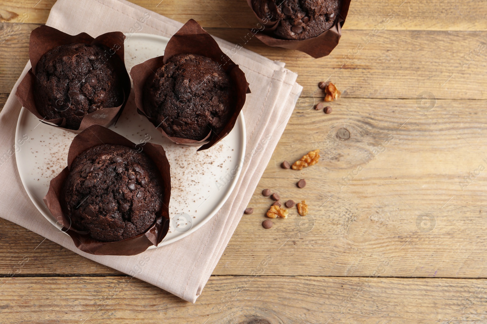 Photo of Tasty chocolate muffins on wooden table, top view. Space for text