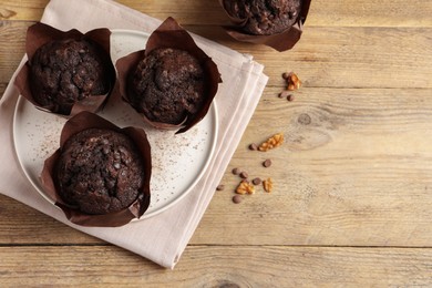 Tasty chocolate muffins on wooden table, top view. Space for text