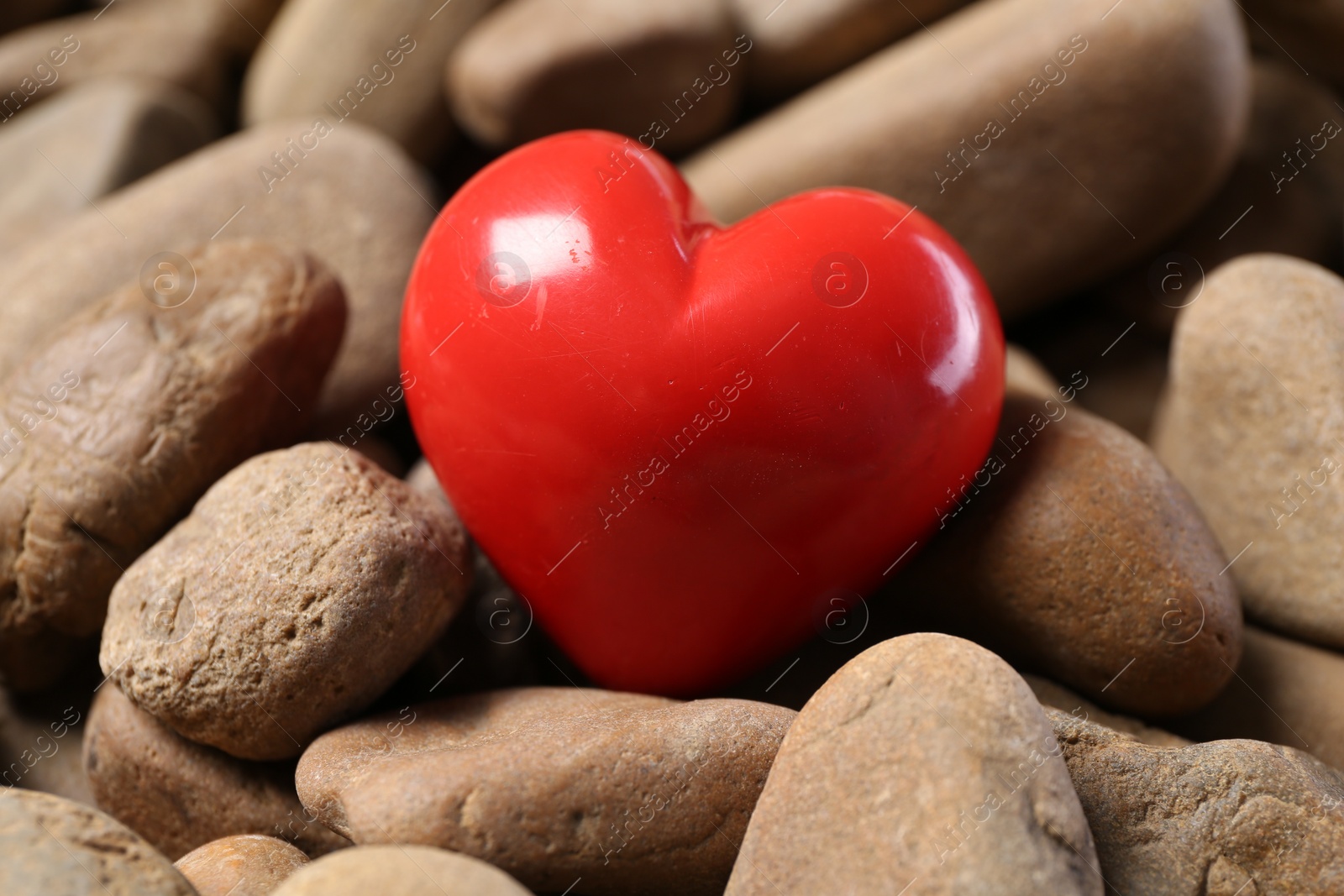 Photo of One red decorative heart on stones, closeup