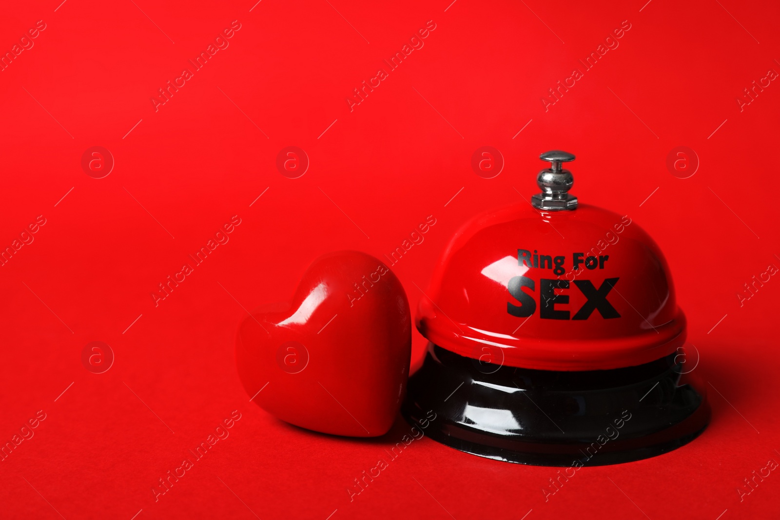 Photo of Sex bell and heart on red background. Space for text