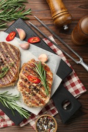 Photo of Delicious grilled pork steaks with spices and meat fork on wooden table, flat lay