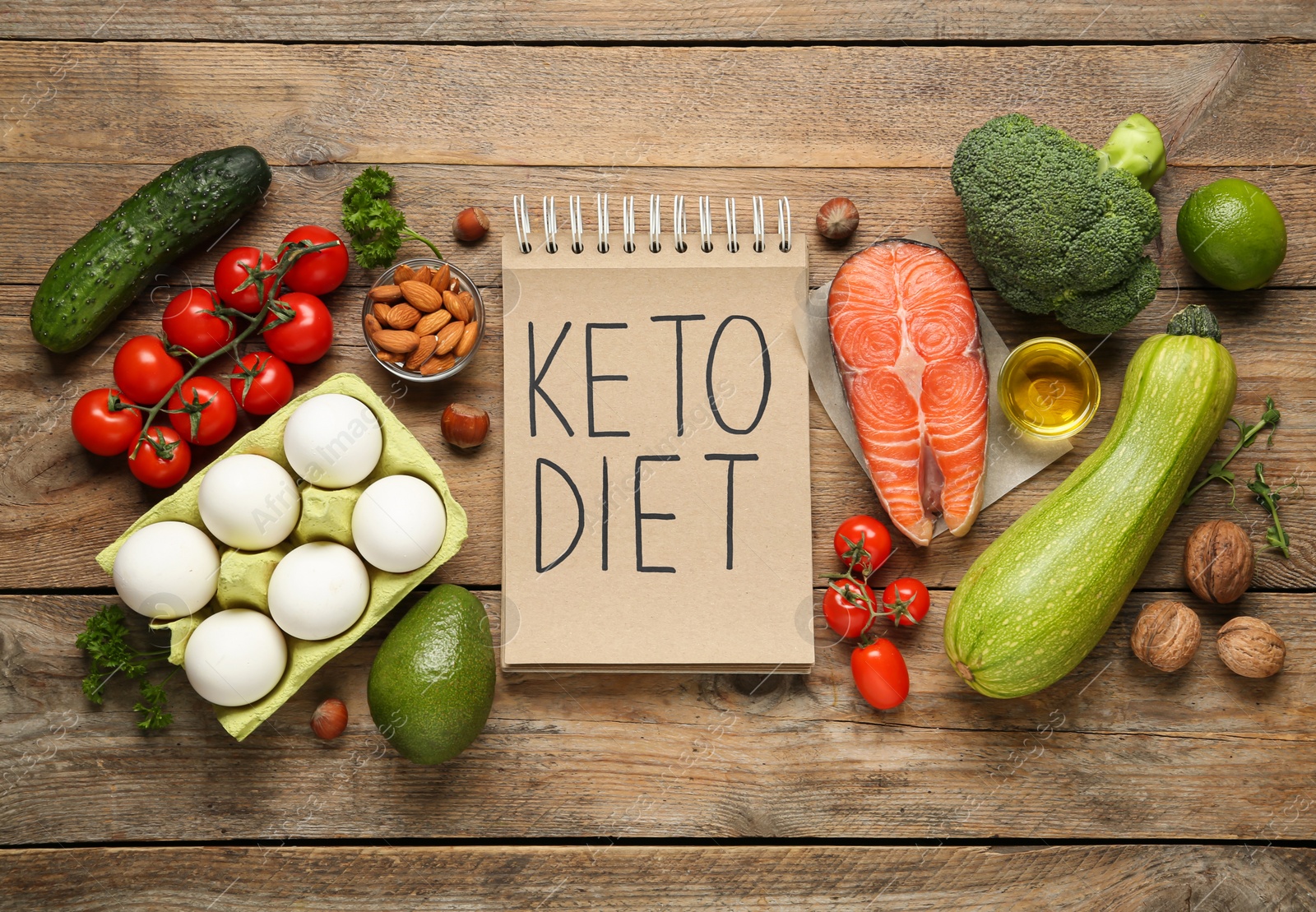 Photo of Notebook with phrase Keto Diet and different products on wooden table, flat lay