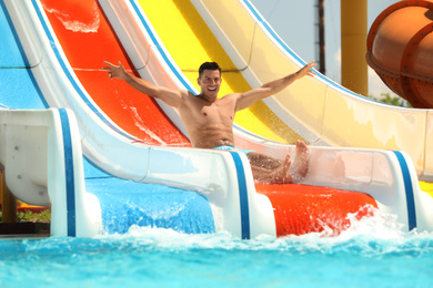 Photo of Man on slide at water park. Summer vacation