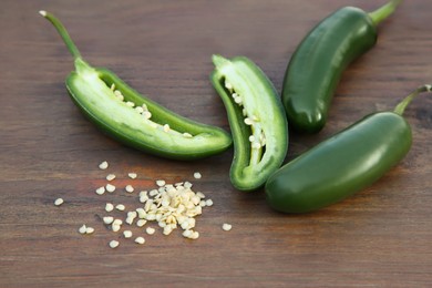 Photo of Fresh green jalapeno peppers and seeds on wooden table, closeup