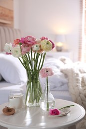 Photo of Beautiful ranunculus flowers on table in bedroom