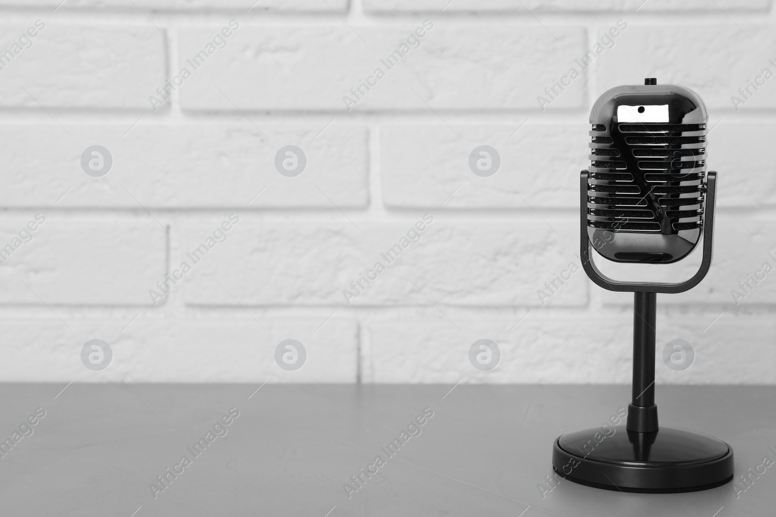 Photo of Retro microphone on table near brick wall. Space for text