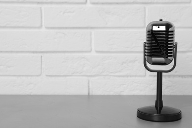 Photo of Retro microphone on table near brick wall. Space for text